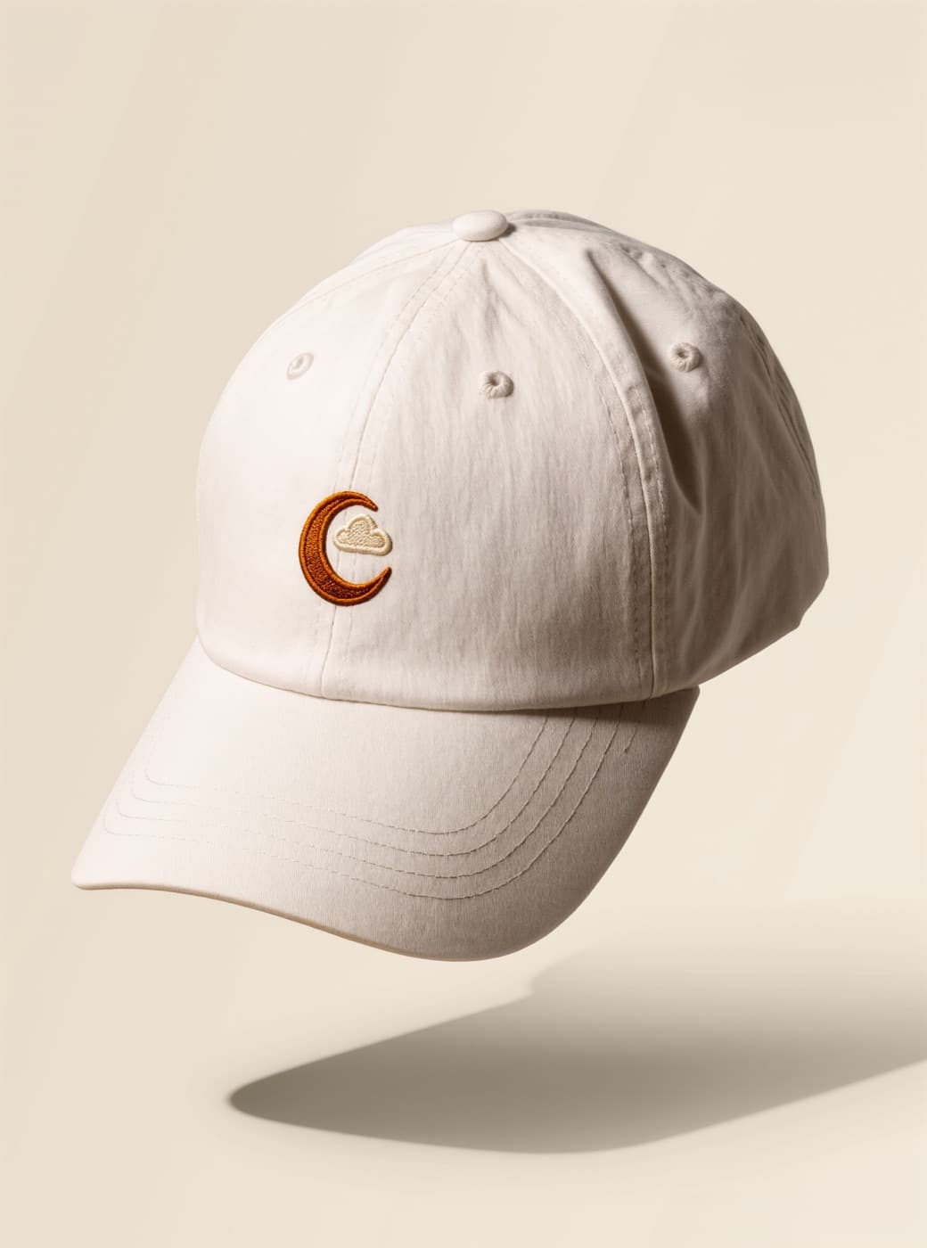 Crescent Cap — a sand-coloured cap with an embroidered crescent motif